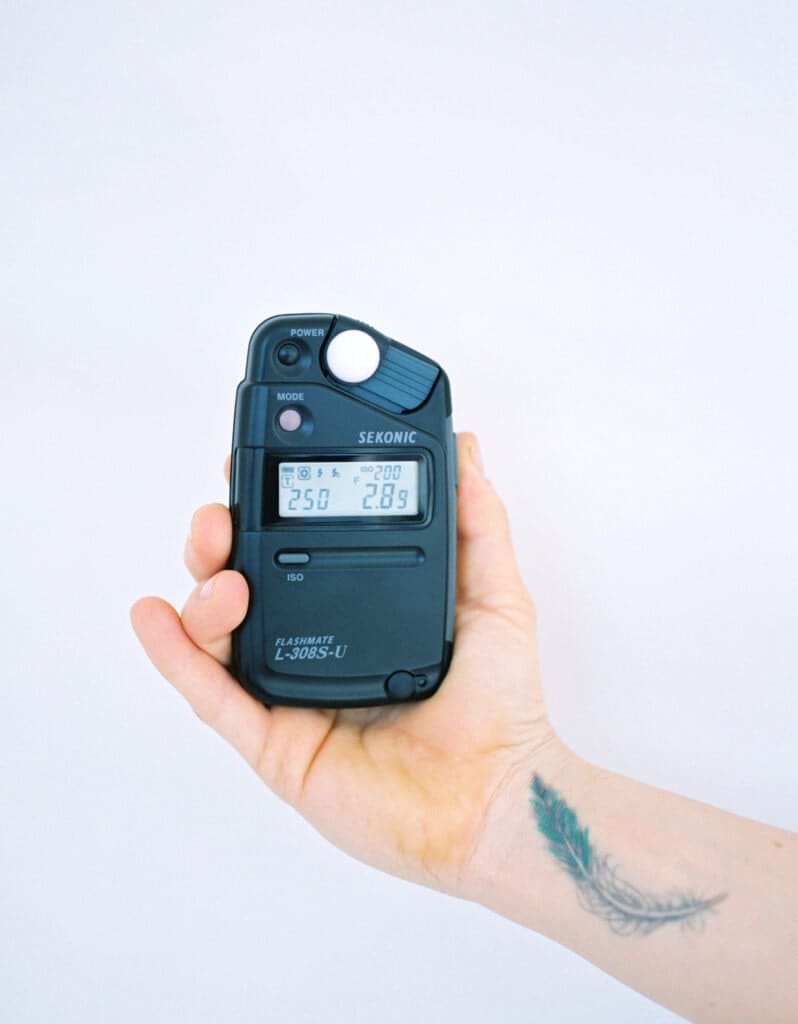A hand holding a black light meter made by Sekonic.